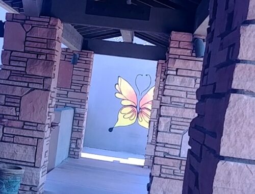 butterfly art on wall down long walkway with stone pillars in sedona arizona