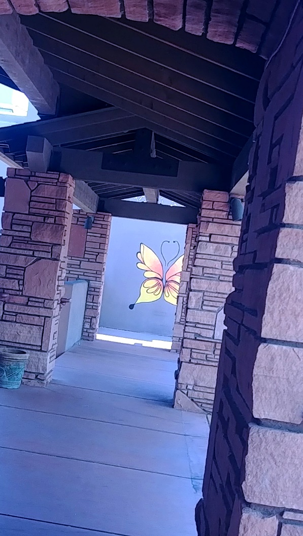 butterfly art on wall down long walkway with stone pillars in sedona arizona